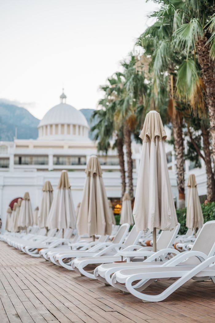 About Elegant resort setting with sun loungers, umbrellas, and palm trees, perfect for a relaxing getaway.